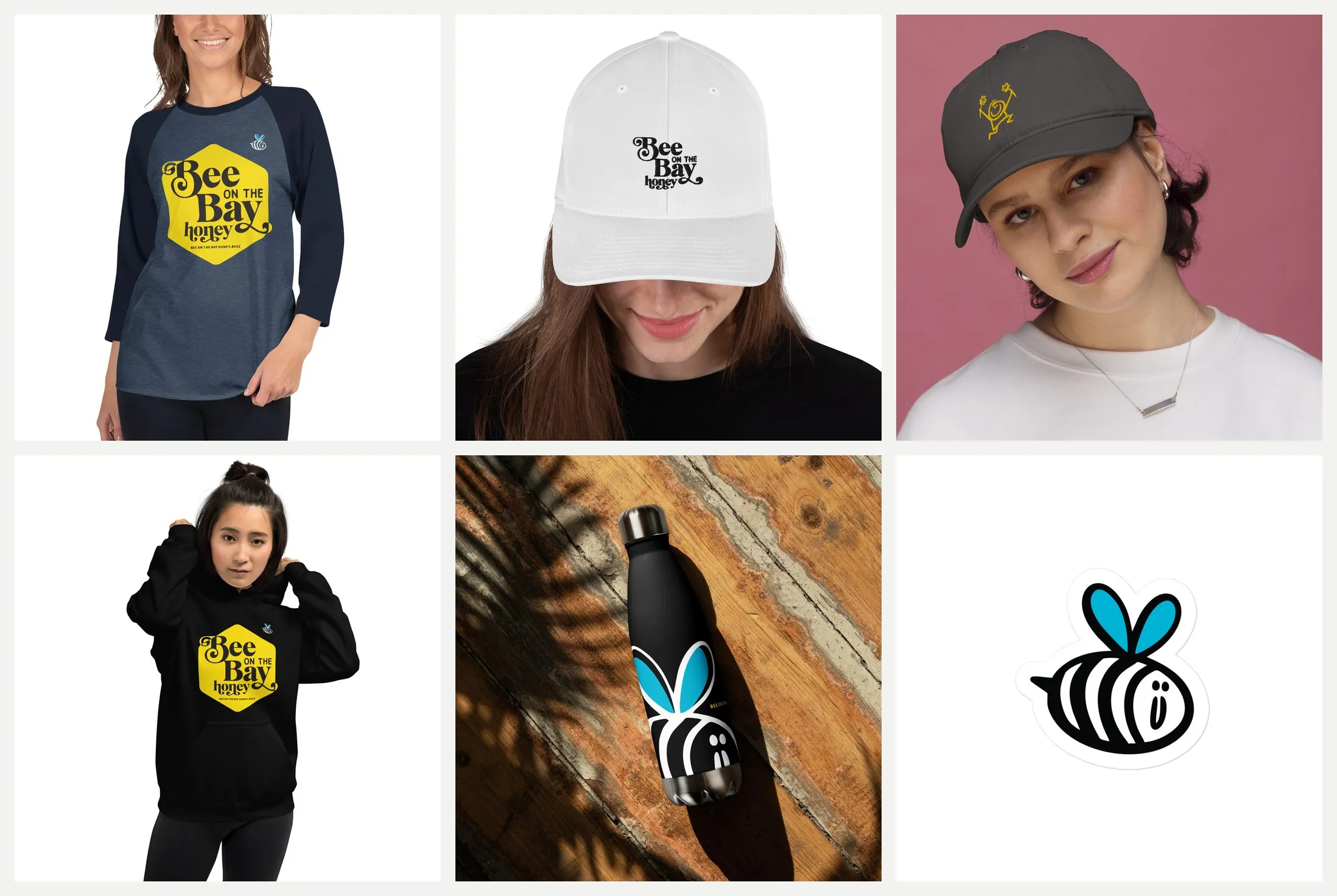 Six pieces of Bee on the Bay swag. A raglan shirt and a black hoodie with the yellow hexagon logo, a white cap with the wordmark, a charcoal cap with an embroidered bee, a black water bottle printed with the bee, and a bee sticker.
